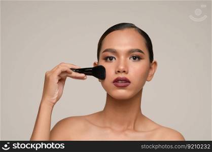 Head shot Portrait, Beauty portrait of asian attractive sensual young woman pose holding makeup blusher brush on her cheek isolated over gray background, copy space