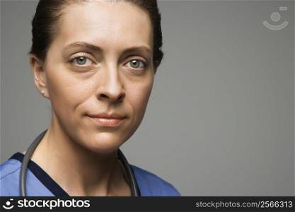 Head shot portrait of Caucasian woman doctor against gray background.