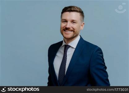 Head shot portrait of happy cheerful business man or male entrepreneur in formal wear looking happy and smiling at camera while standing isolated over light blue background. Career growth concept. Portrait of successful businessman in suit smiling at camera