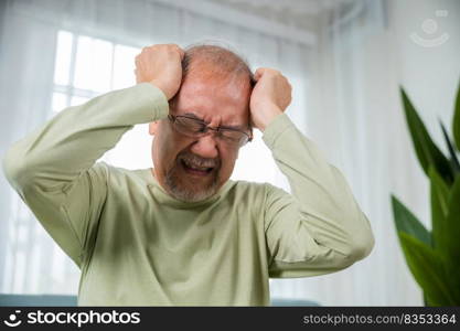 Headache. Close up of elderly holds head with hand suffering from migraine headache, Sad Asian senior man sitting on sofa feeling hurt and lonely at home, Old age health problems, healthcare