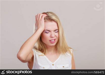 Headache, migraine and stress. Worried business woman upset girl suffering from head pain on gray.
