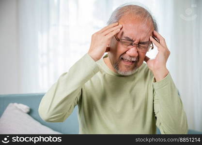 Headache. Sad Asian senior man chronic migraine pain massaging, old man holds head with hand for headache disease in living room at home, Old age health problems, healthcare