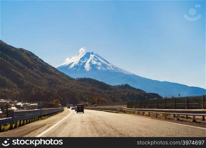 Heading to Mountain Fuji and road in fall foliage in autumn season in transportation concept. Trees in Japan with blue sky background.