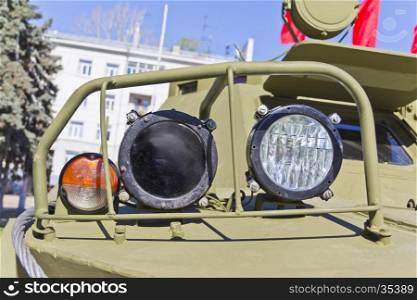 Headlight of military machine at the exhibition under open sky. Headlamp of military transport
