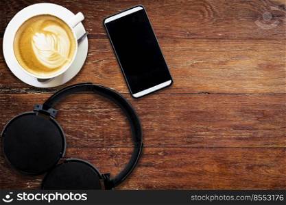 Headphone coffee and phone on wood background and texture with space.