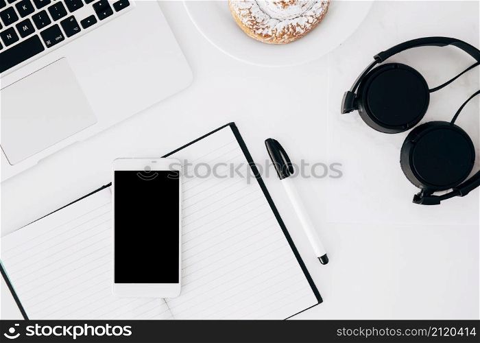 headphone laptop mobilephone diary pen baked food white background