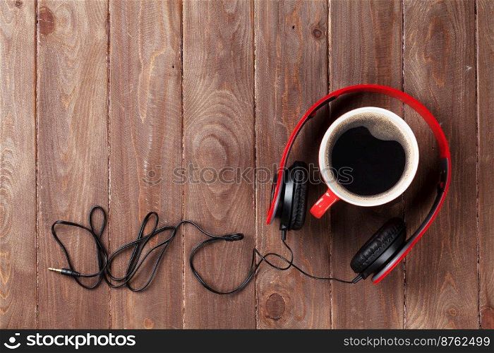 Headphones and coffee cup on wooden desk table. Music concept. Top view with copy space