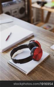 Headphones and notebook at wooden desk table. ?omposer or music creative concept
