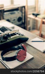 Headphones and vintage old typewriter at wooden desk table. ?omposer or music creative concept