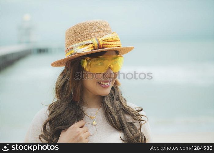 headshot of beautiful asian woman wearing yellow eye glasses standing at sea beach
