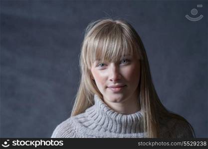 Headshot of blond haired women. Elegant young woman in a jumper on a dark background