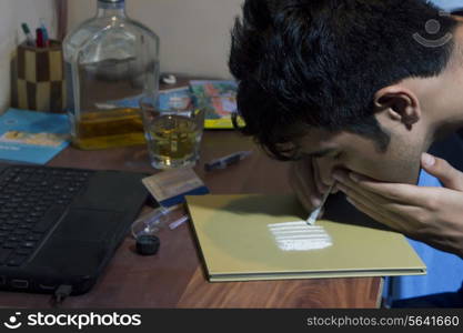 Headshot of man snorting cocaine at home