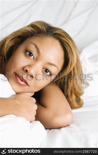 Headshot of pretty woman lying in bed making eye contact.