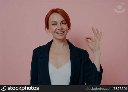 Headshot of young happy sitisfied business woman being sitisfied with choice, showing ok sign, accepting idea, standing isolated on pink studio background. Body language concept. Headshot of young happy sitisfied business woman being sitisfied with choice, showing ok sign