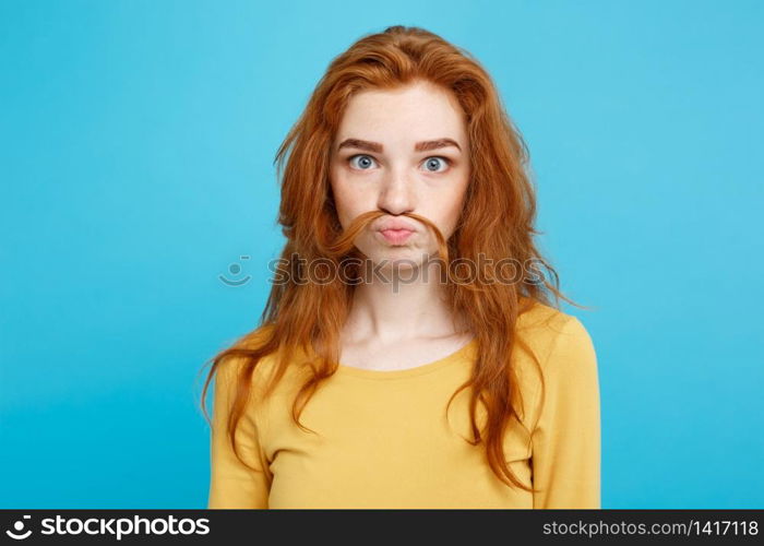 Headshot Portrait of happy ginger red hair girl imitating to be man with hair fake mustache.Pastel blue background. Copy Space.. Headshot Portrait of happy ginger red hair girl imitating to be man with hair fake mustache. Pastel blue background. Copy Space.