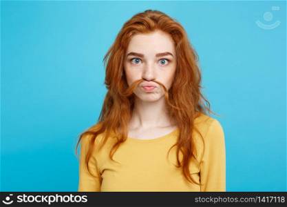 Headshot Portrait of happy ginger red hair girl imitating to be man with hair fake mustache.Pastel blue background. Copy Space.. Headshot Portrait of happy ginger red hair girl imitating to be man with hair fake mustache. Pastel blue background. Copy Space.