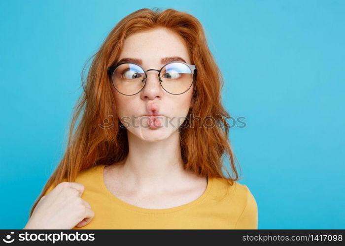 Headshot Portrait of happy ginger red hair girl with freckles smiling looking at camera. Pastel blue background. Copy Space.