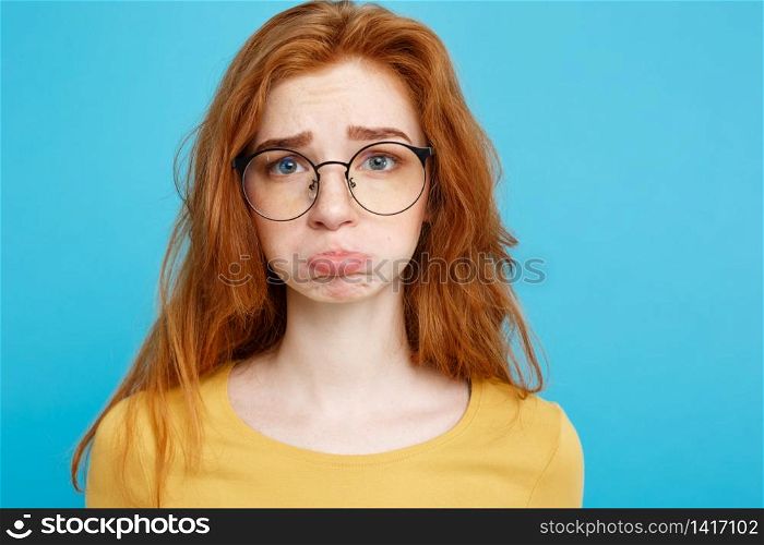 Headshot Portrait of happy ginger red hair girl with freckles smiling looking at camera. Pastel blue background. Copy Space.