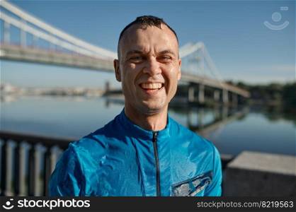 Headshot portrait of happy smiling athlete man runner with wet face looking at camera. Health and fitness running concept. Headshot portrait of smiling athlete man with wet face