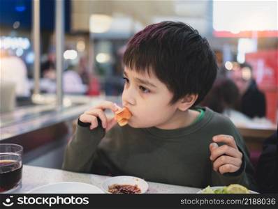 Healhty Young Boy eating Salmon Sashimi in Japanese buffet restaurant , Kid using chopsticks having Japanese food for lunch in the cafe