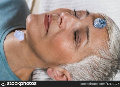 Healing and Balancing Chakras Therapy. Beautiful elderly woman lying on massage table and enjoying chakra healing treatment. Chakra Healing Treatment