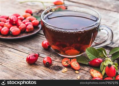 Healing tea with rose hips on a wooden table near red berries. Phytotherapy.. Healing tea with rose hips on a wooden table near red berries.