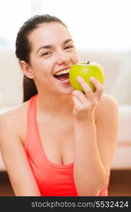 healt, dieting, home and happiness concept - smiling sporty teenage girl with green apple at home