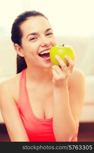 healt, dieting, home and happiness concept - smiling sporty teenage girl with green apple at home