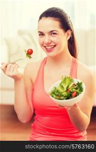 healt, dieting, home and happiness concept - smiling sporty teenage girl with green salad at home
