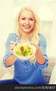 healt, dieting, home and happiness concept - smiling young woman with green salad at home