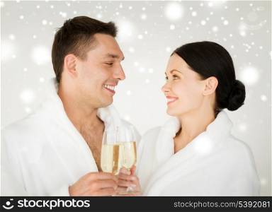 health and beauty, celebration, drinks concept - couple in spa salon in white bathrobes with champagne