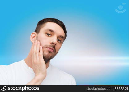 health and beauty concept - beautiful calm man touching his face