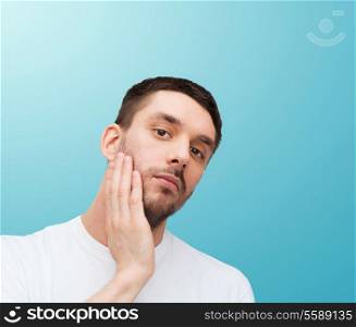 health and beauty concept - beautiful calm man touching his face