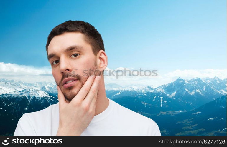 health and beauty concept - beautiful calm man touching his face