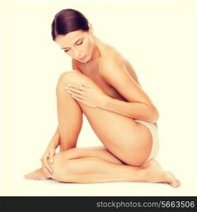 health and beauty concept - beautiful naked woman touching her legs