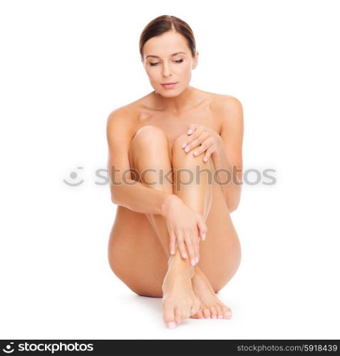 health and beauty concept - beautiful naked woman touching her legs. beautiful naked woman touching her legs