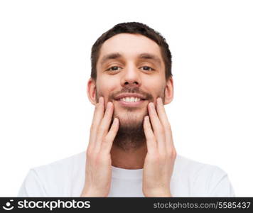 health and beauty concept - beautiful smiling man touching his face