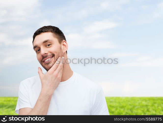 health and beauty concept - beautiful smiling man touching his face