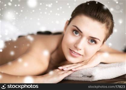 health and beauty concept - beautiful woman in spa salon with hot stones
