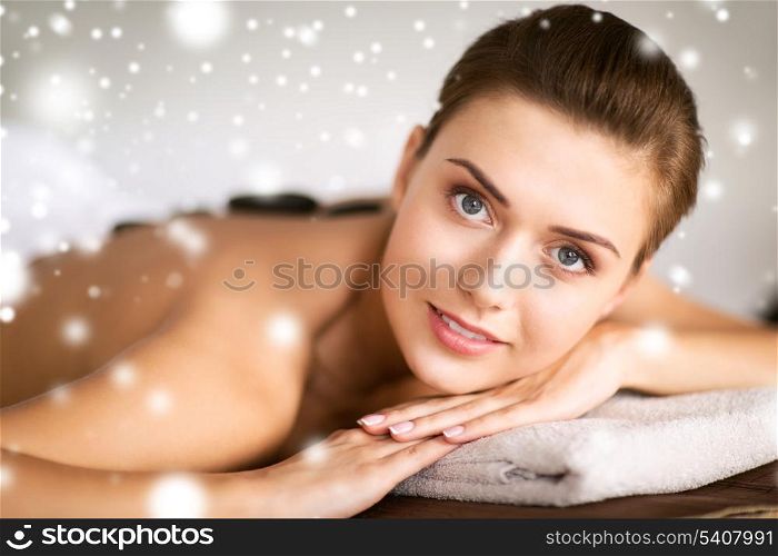 health and beauty concept - beautiful woman in spa salon with hot stones