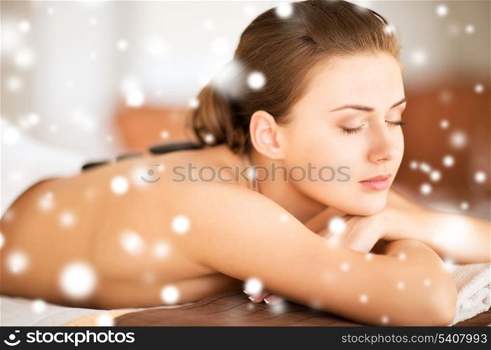 health and beauty concept - - beautiful woman in spa salon with hot stones