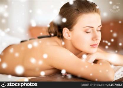 health and beauty concept - - beautiful woman in spa salon with hot stones