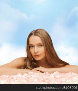 health and beauty concept - beautiful woman with long hair and rose petals