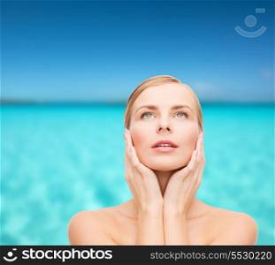 health and beauty concept - beautiful young woman touching her face and looking up
