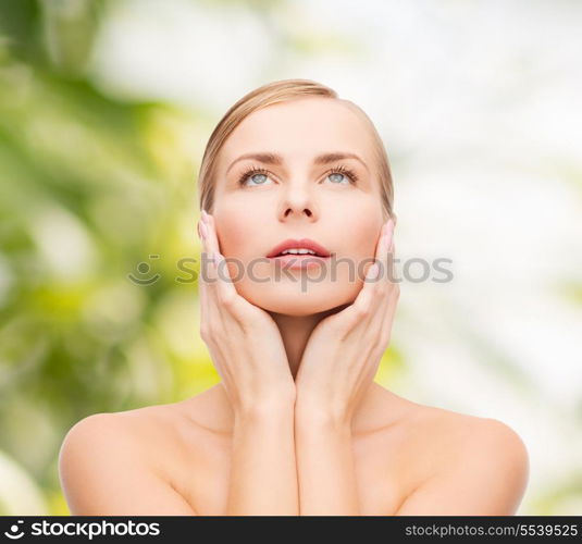 health and beauty concept - beautiful young woman touching her face and looking up