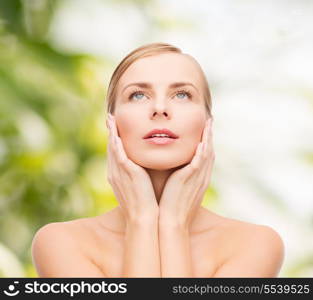 health and beauty concept - beautiful young woman touching her face and looking up