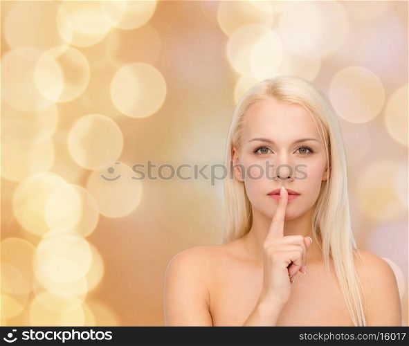 health and beauty concept - calm young woman with finger on lips