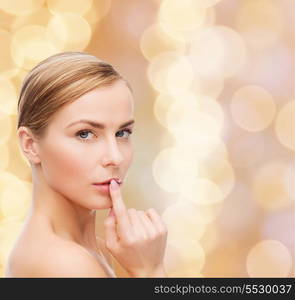 health and beauty concept - clean face of beautiful young woman pointing finger to her lips