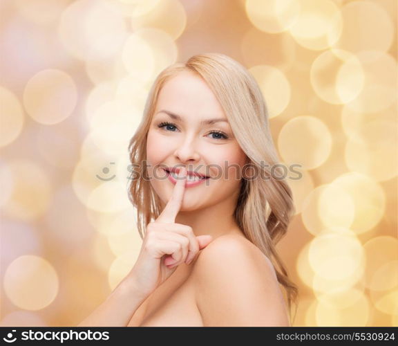 health and beauty concept - clean face of beautiful young woman pointing finger to her lips