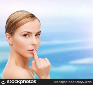health and beauty concept - clean face of beautiful young woman pointing finger to her lips